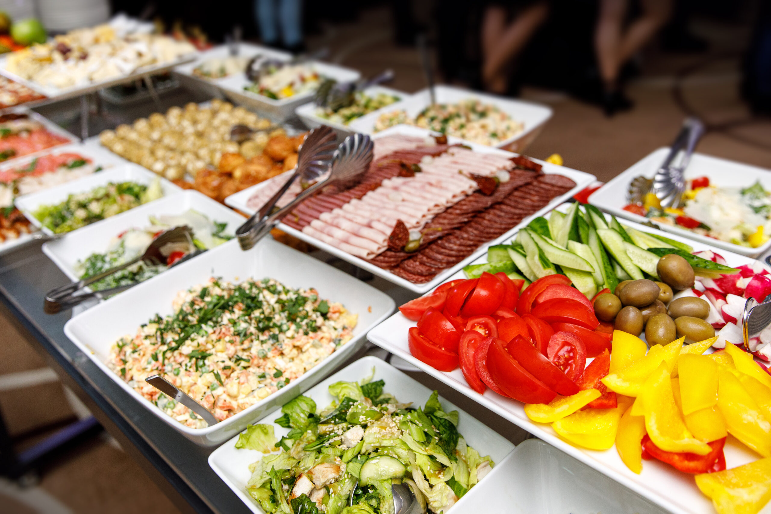 Buffet mit verschiedenen Salaten, frischem Gemüse und Aufschnitt auf weißen Platten